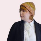 Person wearing colorful knit beanie in side profile on a plain background