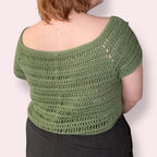Person wearing green crochet top back view plain background
