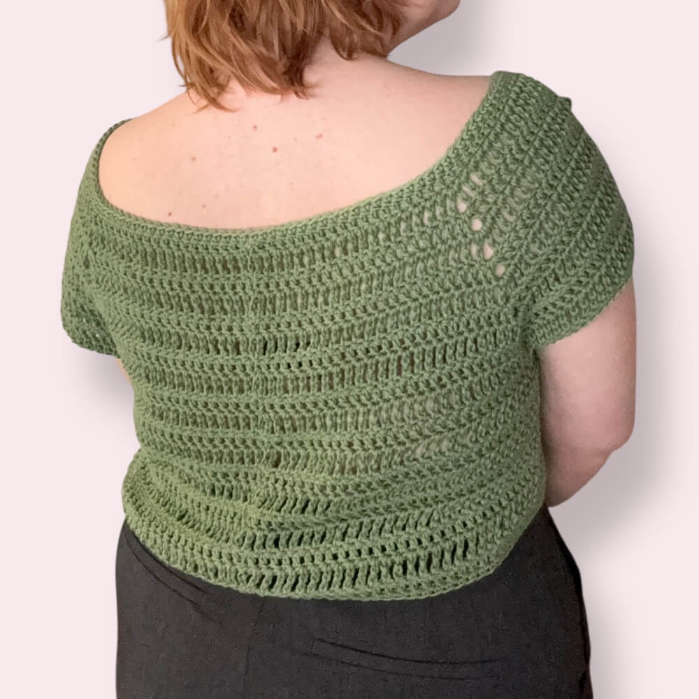Person wearing green crochet top back view plain background