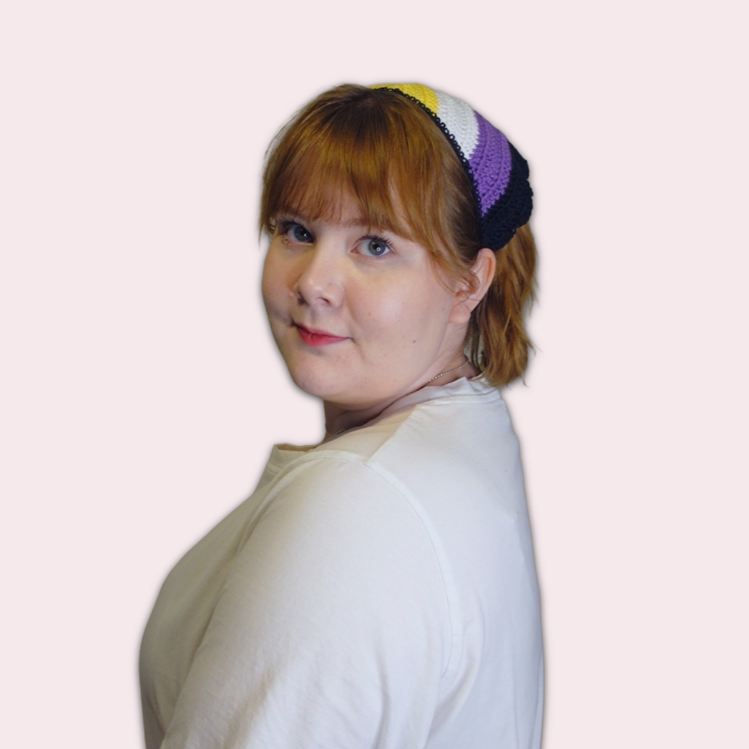 Person wearing nonbinary pride crocheted bandana on plain background