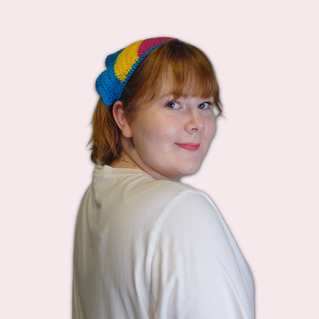 Person wearing pan pride crochet bandana on plain background