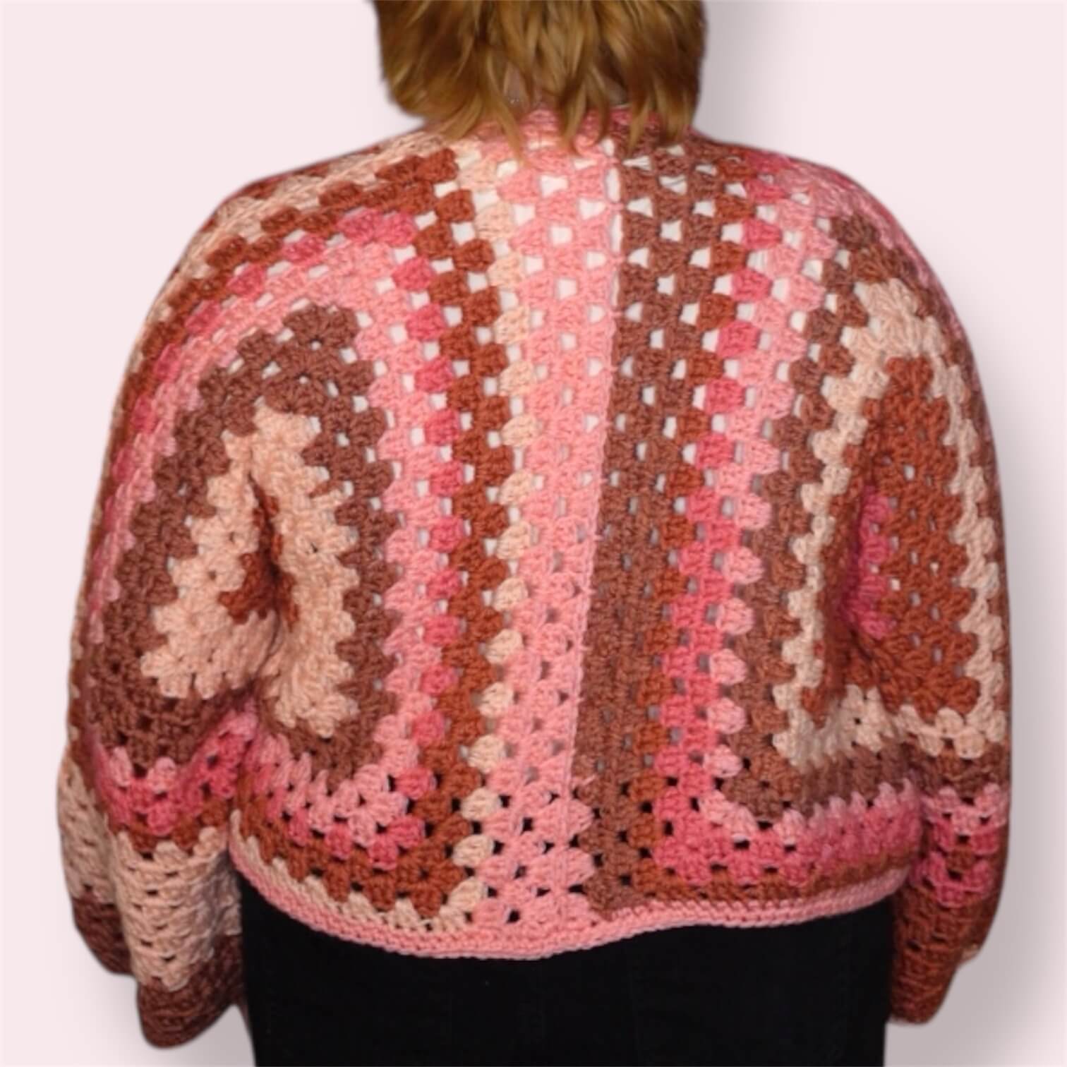 Person wearing pink crochet cardigan back view
