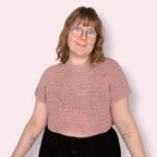 Person wearing pink crochet tshirt on plain background