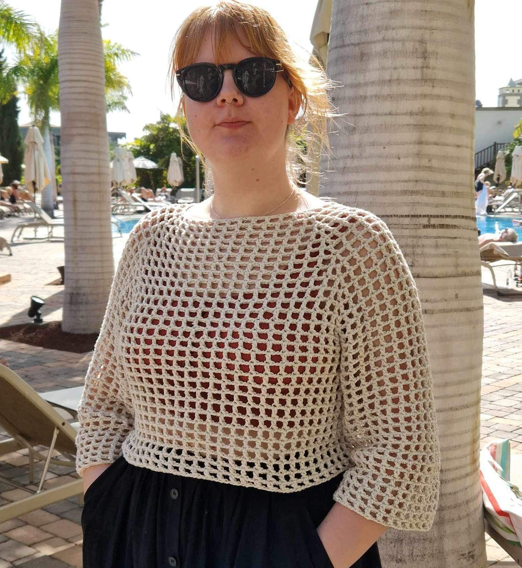 Person wearing white crocheted top in sunny surroundings