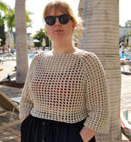 Person wearing white crocheted top in sunny surroundings