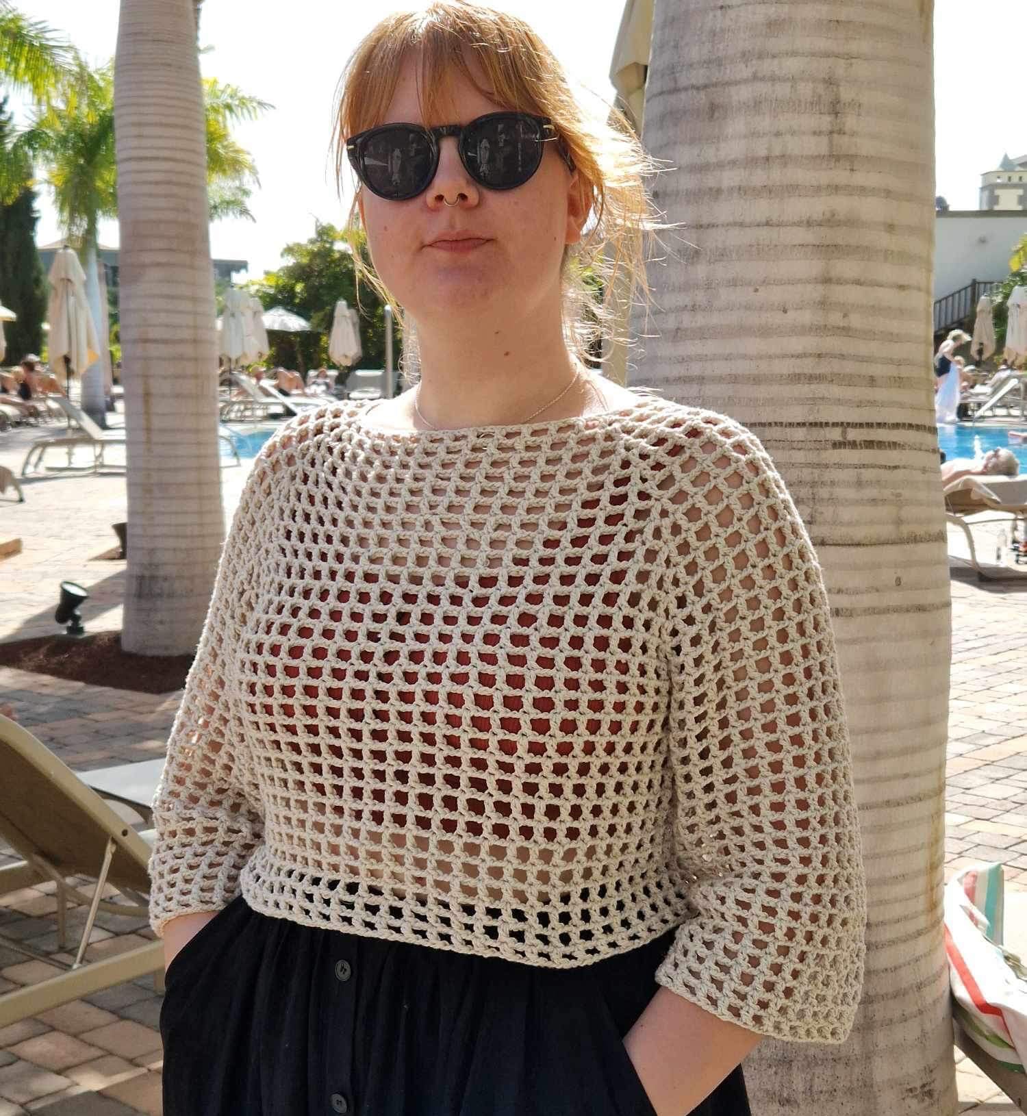 Person wearing white crocheted top in sunny surroundings