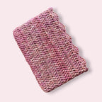 Pink crochet book sleeve on plain background
