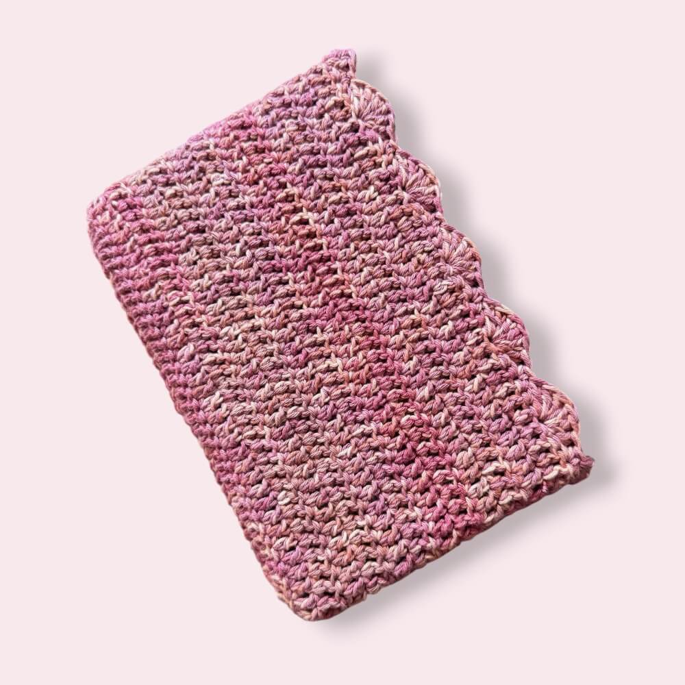Pink crochet book sleeve on plain background