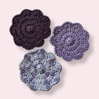 Purple crocheted coasters on plain background