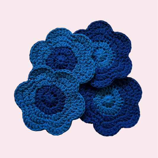 Set of 4 flower-shaped crochet coasters on a pink background