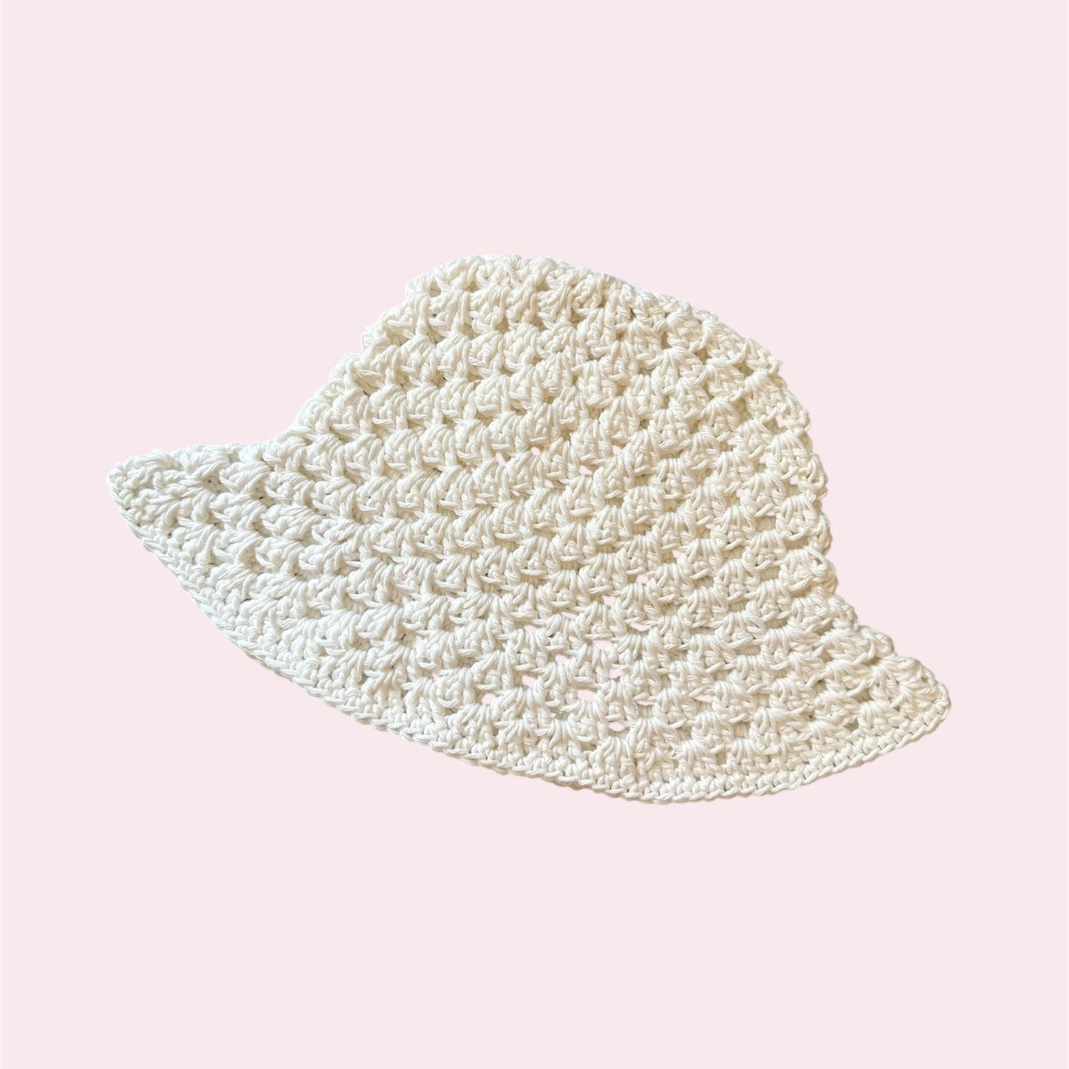 White crochet bucket hat on a light pink background