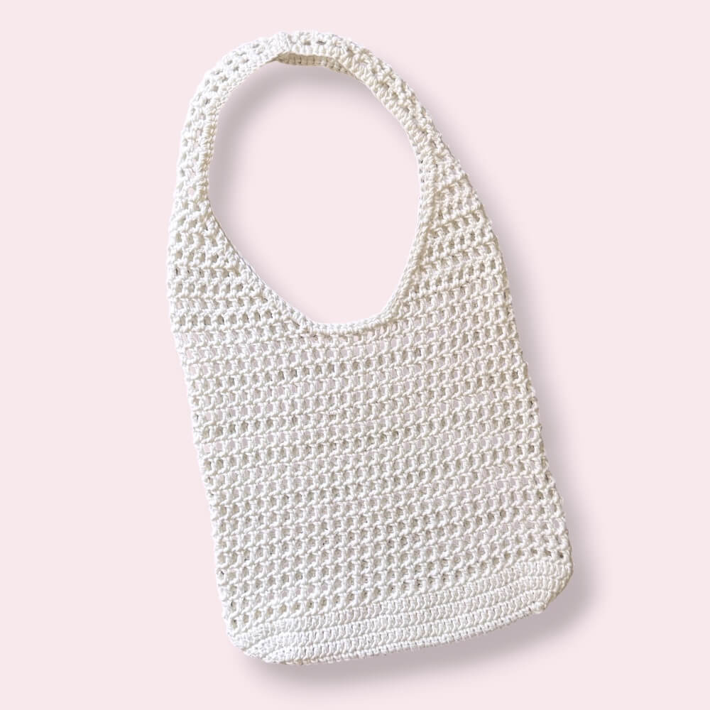 White crochet mesh tote bag on plain background