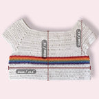 White crochet top with rainbow stripe and measurement labels on a light pink background