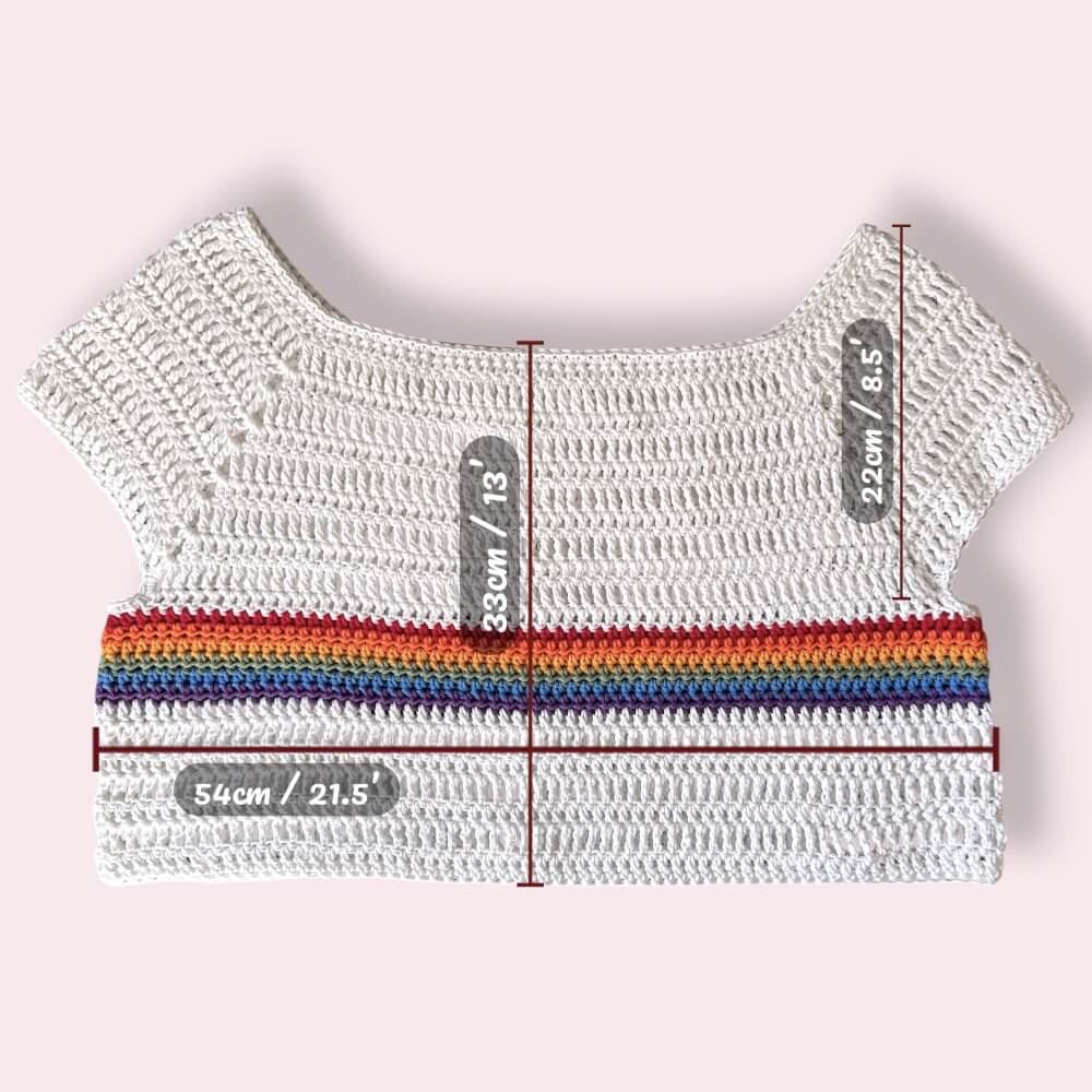 White crochet top with rainbow stripe and measurement labels on a light pink background