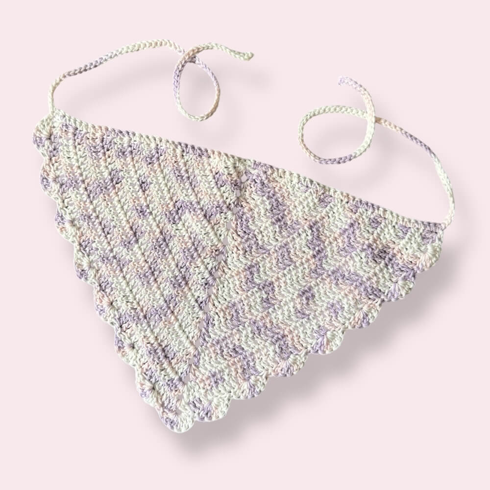 White, pastel pink and pastel purple crochet bandana on plain background
