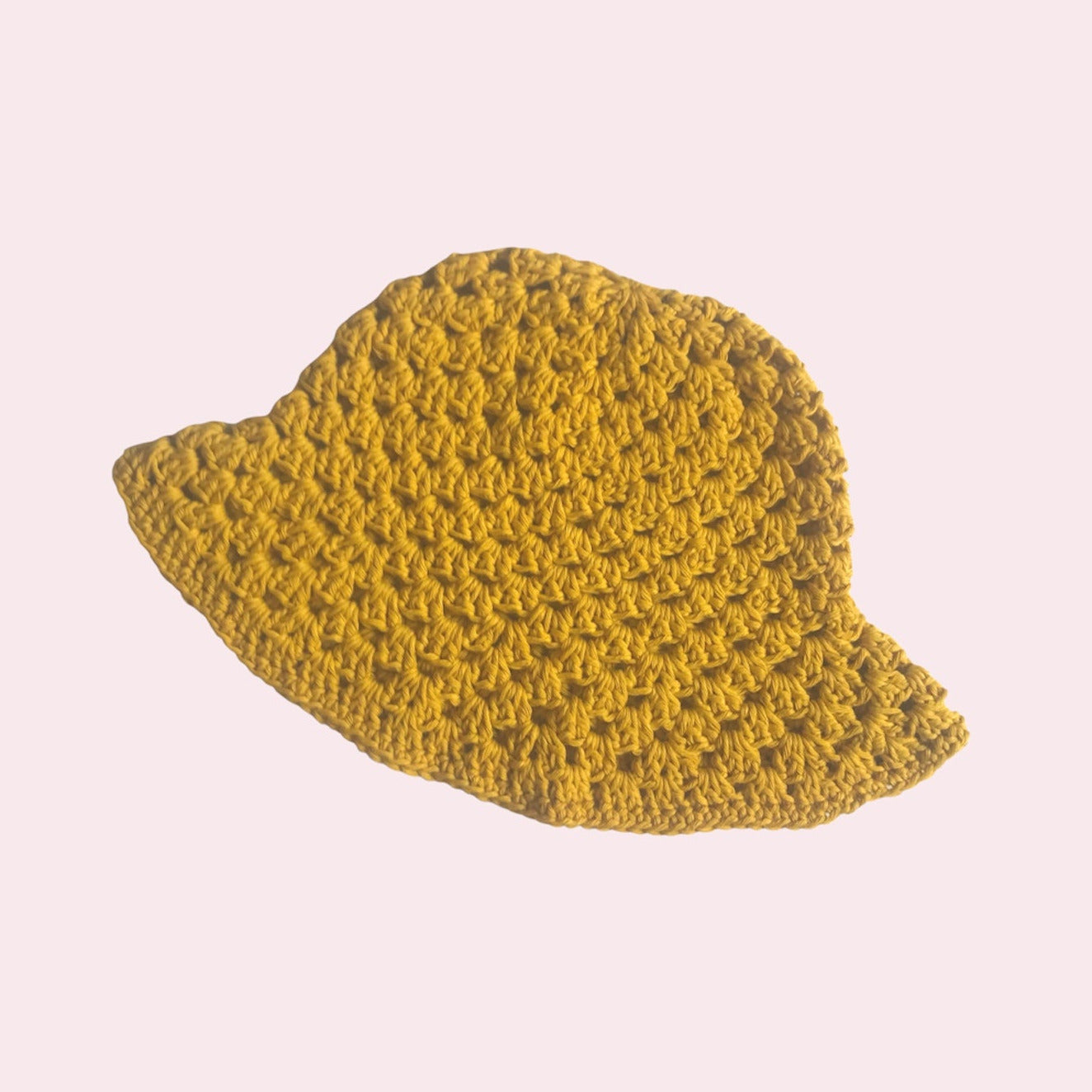 Yellow crochet bucket hat on pink background