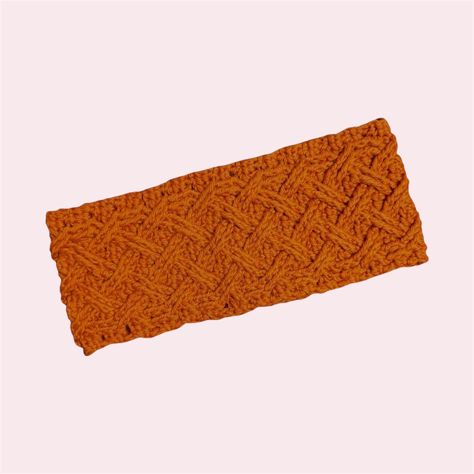 textured orange crochet earwarmer headband on a pink background